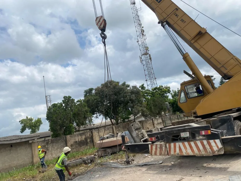 50-tonne mobile crane rigging a heavy roller onto a trailer while crew in hi-vis vests guide the load